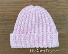 a pink and white knitted hat sitting on top of a wooden table