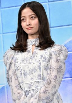 a woman standing in front of a blue tile wall with her hands on her hips