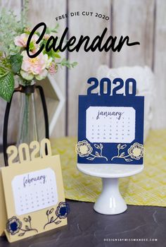 a calendar sitting on top of a table next to a vase with flowers in it