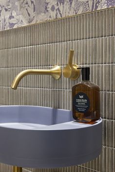 a sink with a soap dispenser next to it on a tiled wall