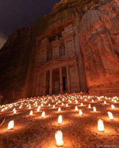 many lit candles in front of a rock formation