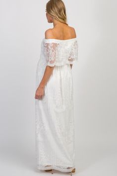 a woman wearing a white dress with off the shoulder sleeves and lace detailing on it