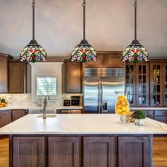 a kitchen with three lights hanging from the ceiling and wooden cabinets in front of it