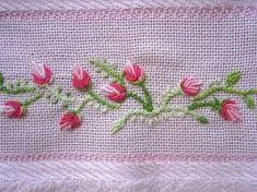 some pink flowers and green leaves on a white cloth with stitched border in the middle