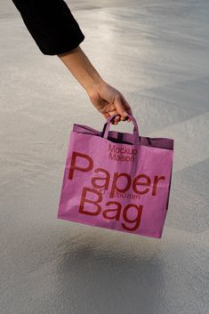 a person holding a pink paper bag on top of the ground in front of them