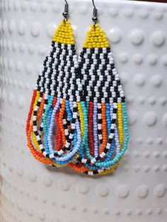 a pair of colorful beaded earrings hanging from a hook on a white cup with polka dots