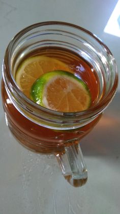 a glass mug filled with liquid and sliced oranges