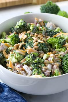 a white bowl filled with broccoli and chicken salad on top of a table