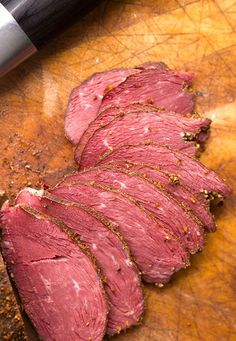 sliced meat sitting on top of a wooden cutting board