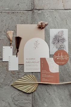 the wedding stationery is laid out on top of the stone wall, including cards and tassels