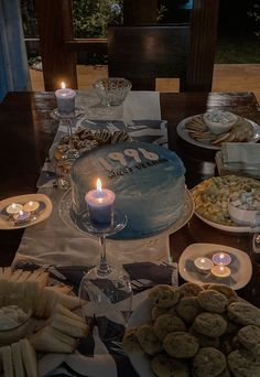 a table filled with cookies and candles on top of it's wooden table covered in plates