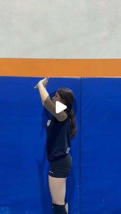 a woman standing on top of a blue and orange wall