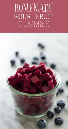 a glass bowl filled with blueberries next to some cut up pieces of red food