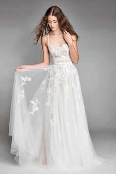 a woman in a white wedding dress is posing with her veil over her shoulder and looking down at the floor