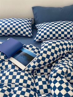 a blue and white checkered comforter on a bed with an electronic device sitting on it