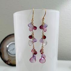 Our iconic earrings are now composed of mystic pink topaz, mystic pink quartz, garnet, rhodolite garnet and light amethyst gemstones. The largest gem measures approximately 10 mm across. These earrings resemble a previous pair with slightly different nuances. This set has a simple profile and measures a little longer than the previous rendition. These earrings are finished in gold vermeil and completed with simple ball-end earwires. Earrings measure approximately 2¼-inches from the bottom of the earwire. Handmade by me in San Francisco, CA, USA. Item ships in a leatherette jewelry box with Blue Easel Designs logo via USPS Priority Mail with Delivery Confirmation and shipping insurance. Find more designs at www.blueeaseldesigns.com Amethyst Multi-stone Briolette Earrings, Amethyst Multi-stone Earrings As Gift, Tourmaline Multi-stone Earrings As Gift, Tourmaline Multi-stone Earrings For Gift, Multi-stone Tourmaline Earrings As A Gift, Pink Amethyst Gemstones As A Gift, Simple Profile, Cluster Jewelry, Light Amethyst