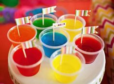 there are many cups with different colored drinks on the table and straws sticking out of them