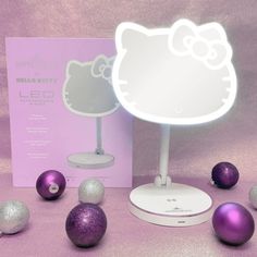 the hello kitty light up mirror is next to some christmas balls and ornaments in front of it