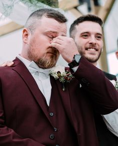 two men standing next to each other and one is covering his face with his hand