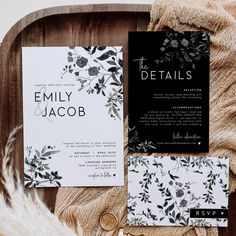 the wedding stationery is laid out on top of a wooden tray with feathers and flowers