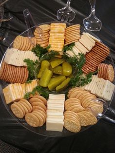 a platter filled with crackers, cheese and pickles