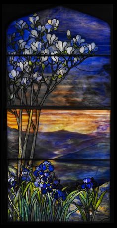 a stained glass window with blue flowers in the foreground and an orange sky in the background