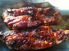 two pieces of meat sitting on top of a pan covered in bbq barbecue sauce