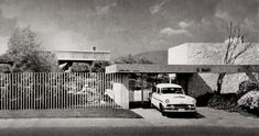 an old car is parked in front of a house with a fence and trees on the other side