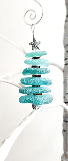 a glass ornament hanging from a tree branch with a starfish on it