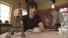 a man sitting at a table with a cup and saucer in front of the eiffel tower