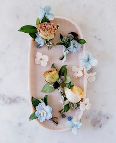 a tray with flowers on it sitting on a marble counter top next to blue and white flowers