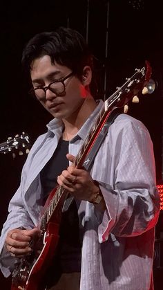 a man with glasses playing an electric guitar