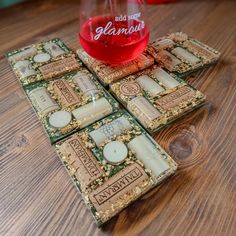 three coasters sitting on top of a wooden table next to a glass filled with liquid