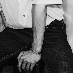 a black and white photo of a man with his hand on the back of a chair