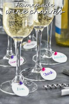 wine glasses with name tags on them sitting next to bottles and corkscrews