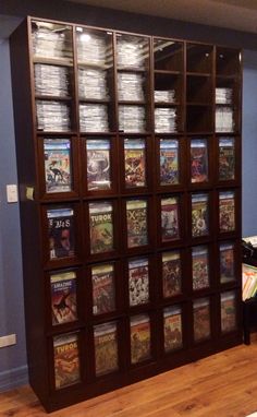 a book case filled with lots of books on top of a hard wood floor next to a blue wall