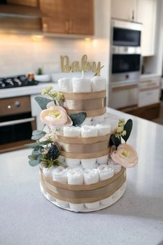 a three tiered cake decorated with baby diapers and flowers on a kitchen counter