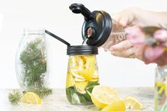 a person pouring water into a jar filled with lemon slices