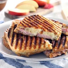 a grilled sandwich on a plate with apples in the background