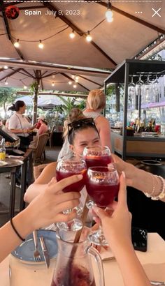 two women toasting with wine glasses in front of them at an outdoor dining area