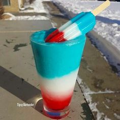 a blue, red and white drink sitting on top of a sidewalk next to snow