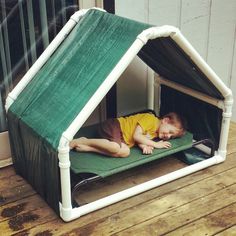 a young boy laying on top of a green mat in a house shaped like a tent