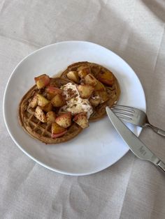 a white plate topped with waffles covered in toppings next to a fork