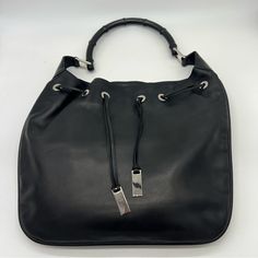 Gucci Black Leather Shoulder Bag With Black Bamboo Handle And A Woven Leather Cinch On Top. Measurements: Height: 14.5 " Length: 16 " Depth: Up To 7 " Handle Drop: 11 " This Shoulder Bag Features A Leather Body, A Bamboo Handle, An Open Top With Drawstring Closure, And An Interior Zip Pocket. It Is In Very Good Condition. No Tears, Holes, Stains, Or Discoloration. The Only Flaws With It Are A Few Very Small Marks/Scratches As Seen In The Photos. They Are Very Minimal And Are Really Only Visible Black Leather Shoulder Bag, Black Bamboo, Top Measurements, Bamboo Handles, Gucci Black, Open Top, Gucci Bag, Leather Shoulder Bag, Black Silver