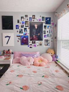 there is a bed with pink pillows and pictures on the wall above it, along with stuffed animals