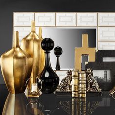 gold and black vases are sitting on a table in front of a large mirror