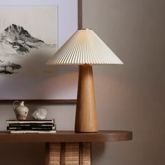 a table lamp sitting on top of a wooden shelf next to a vase and books