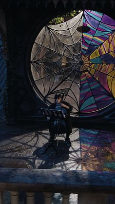 a person sitting on a bench in front of a large window with colorful art behind them