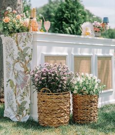 two baskets filled with flowers sitting on top of a grass covered field next to a white fence