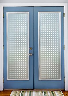 a blue door with two glass panels and a rug on the floor in front of it